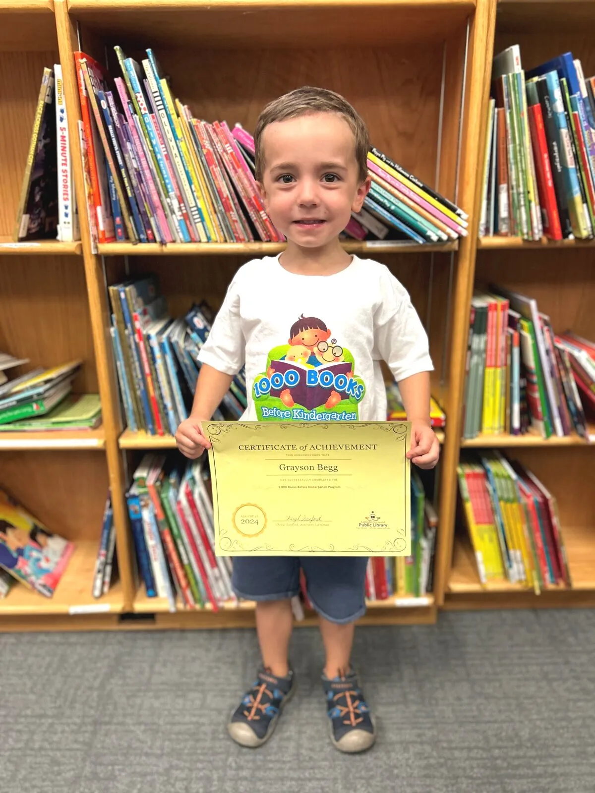 Child holding 1000 Books Before Kindergarten certificate