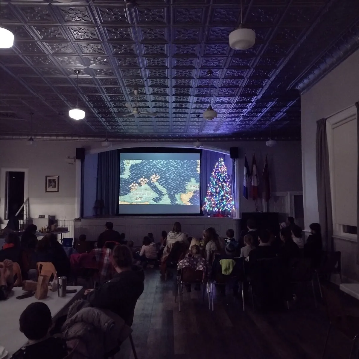 Children and adults watching a holiday film in a decorated community hall