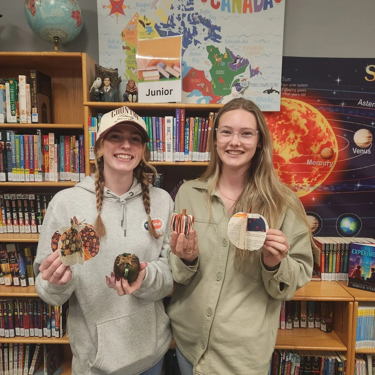 Two students displaying handmade bookmarks at the library